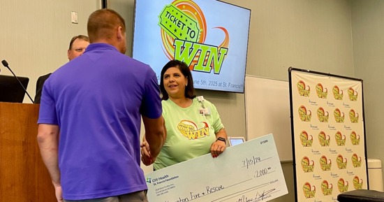 Brad Bell, Foundation Chairman and Melissa Griffith, CHI Health Foundation Director, present Hampton Fire and Rescue representative Dane Schafer a check for $2,000 for replacement helmets and lights. 